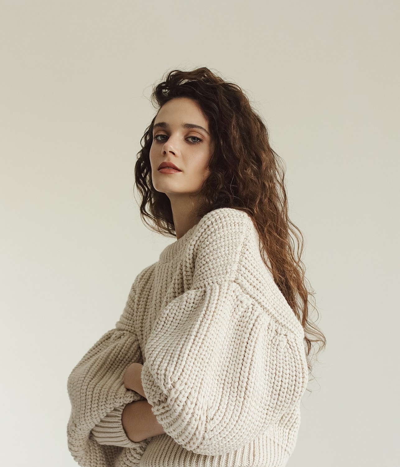 Model in cozy knit sweater posing thoughtfully.