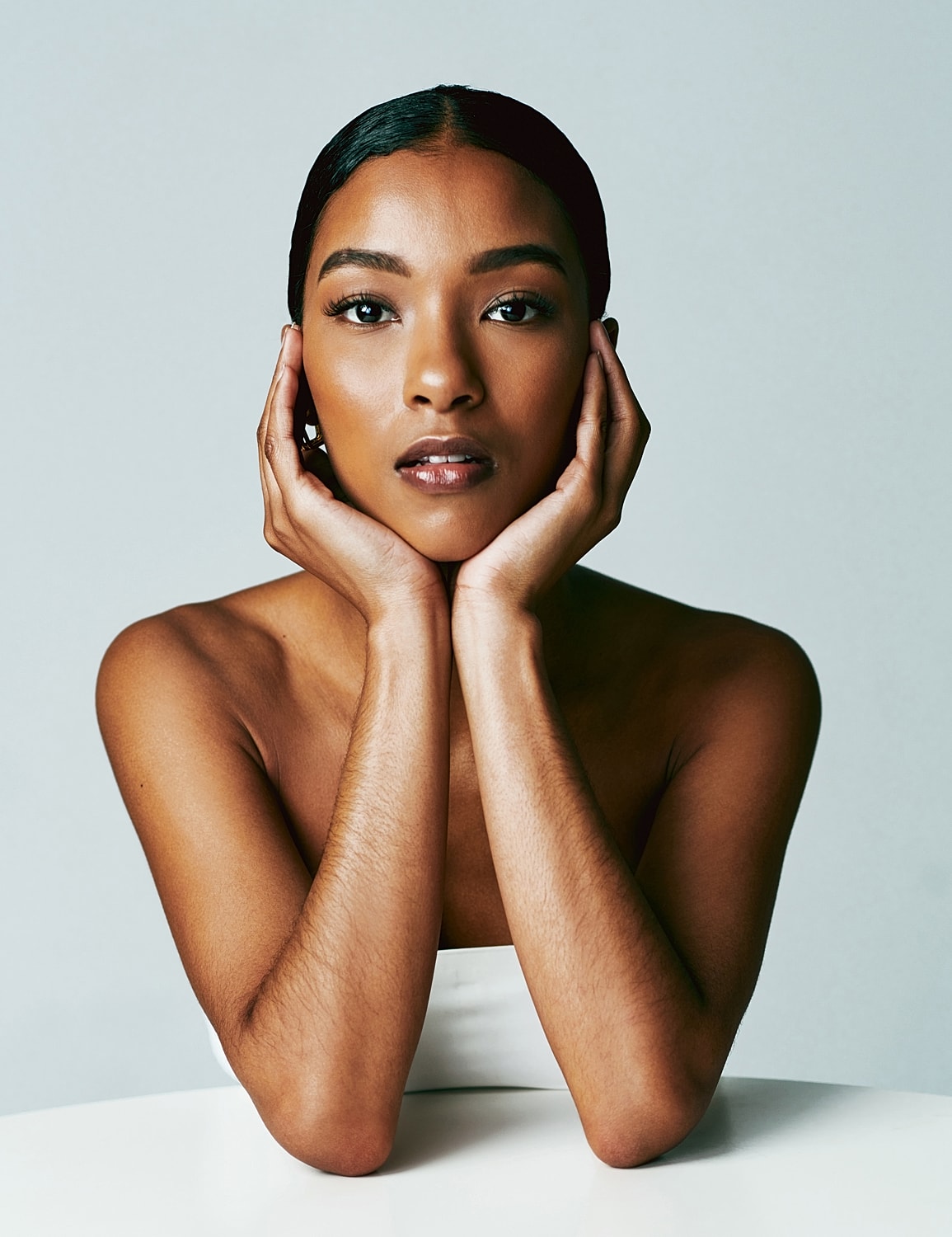 Woman in casual shirt and ripped jeans, smiling.